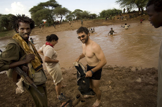 New York Times correspondent Jeffrey Gettleman, in Somalia crossing a river with rebel fighter Commander Peacock, a “heavily armed dreamer.” (KenyaBuzz)